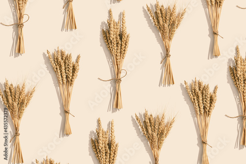 Bunch of ripe wheat ears close up  on beige background. Creative autumn harvest of grain crops photo