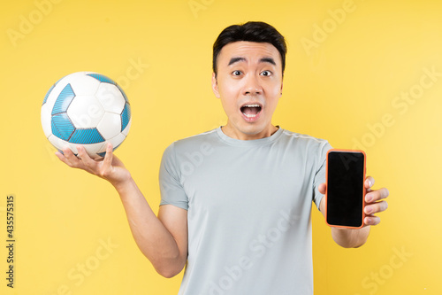 Asian man holding ball and phone in hand