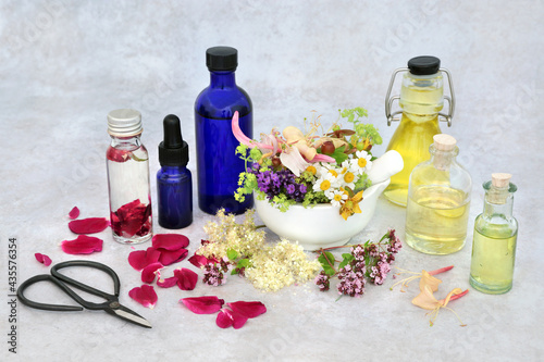Summer herb & flower selection for preparing aromatherapy essential oils with oil bottles and flowers in a mortar with pestle and loose. Herbal plant medicine health care concept.