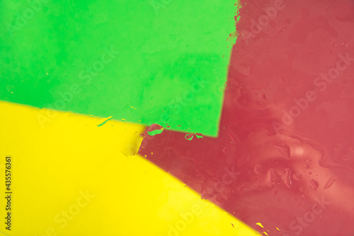 Multicolored background of green, yellow and red with strains and drops of water. Abstract bright and colorful backdrop