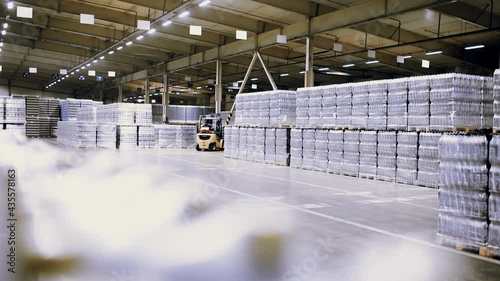loader on the background of a huge industrial food warehouse with plastic PET bottles with beer,  water,  drinks. photo