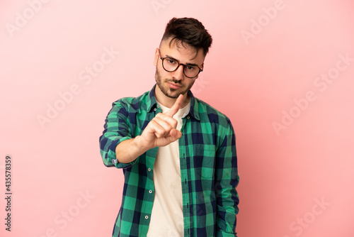 Young caucasian man isolated on pink background frustrated and pointing to the front