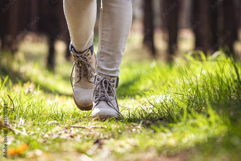 Hiking boot. Hiker walking in forest. Female legs wearing leather sports shoe in woodland