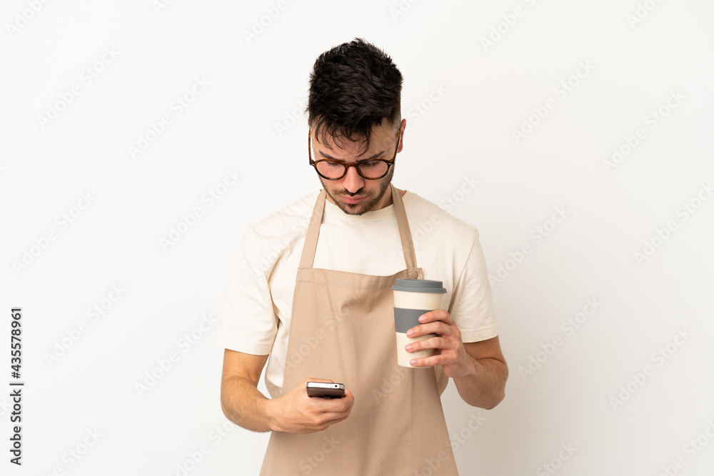 Restaurant waiter caucasian man isolated on white background holding coffee to take away and a mobile