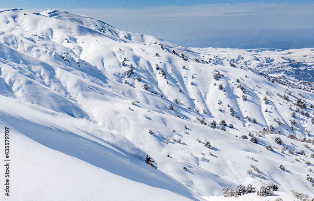 Snowboarder rides on fresh snow against the backdrop of mountains and gorges Snowboarder rides on fresh snow against the backdrop of mountains and gorges