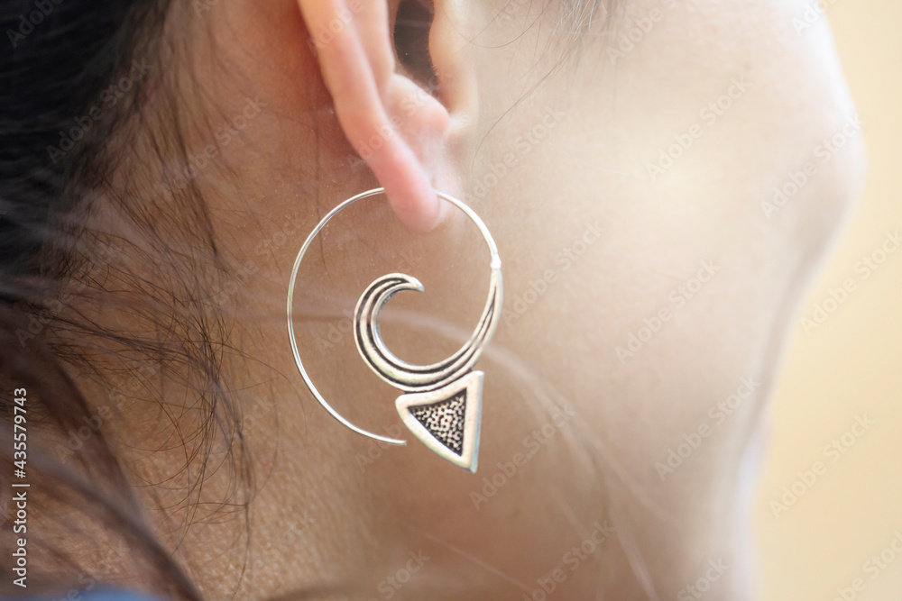 Fototapeta premium Girl wearing silver plated brass Indian earrings in spiral shape