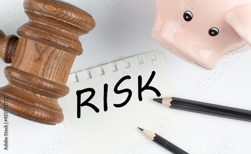 RISK text on paper with gavel and piggi bank photo