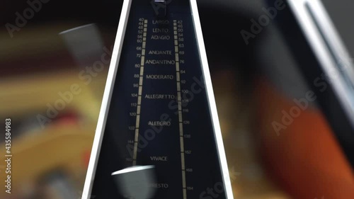 Metronome with pendulum fast in motion, to keep rhythm and tempo for piano, classical music,  musicians - close-up with selective focus photo