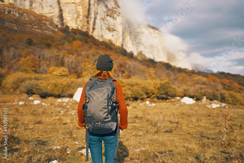 a traveler with a backpack in a denim hat are walking on the nature mountains