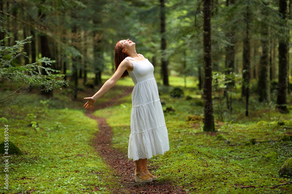 Woman in white dress celebrating in a green forest Woman in white dress celebrating in a green forest