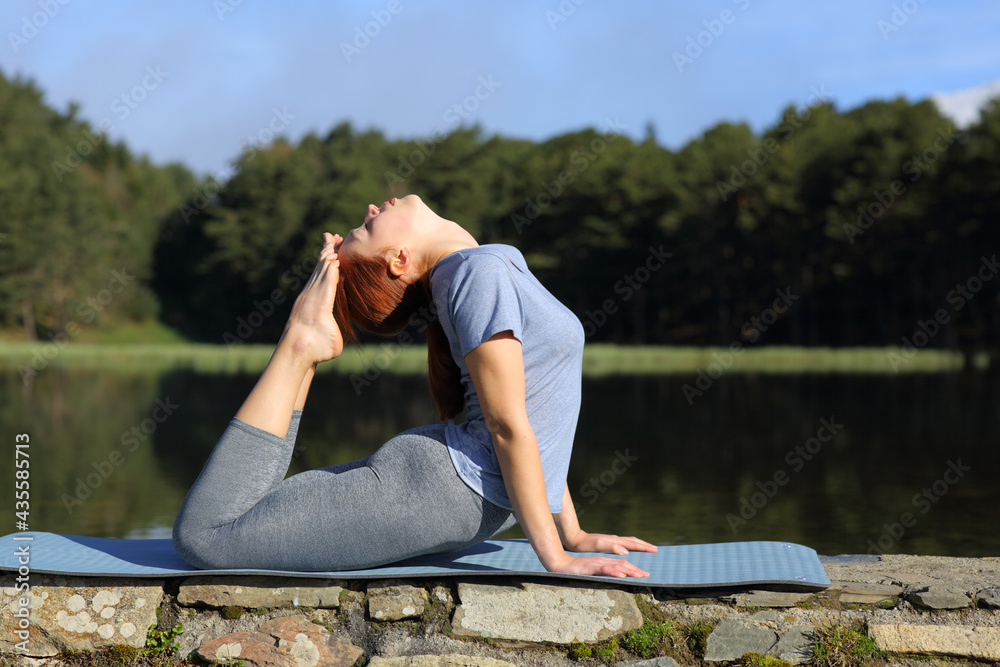 Woman practicing yoga pose in a lake in the mountain