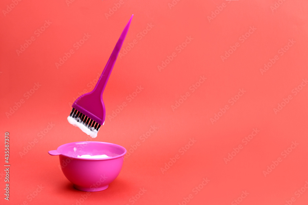 brush levitating over a plastic bowl of hair dye on a red background. Copy space for text brush levitating over a plastic bowl of hair dye on a red background. Copy space for text