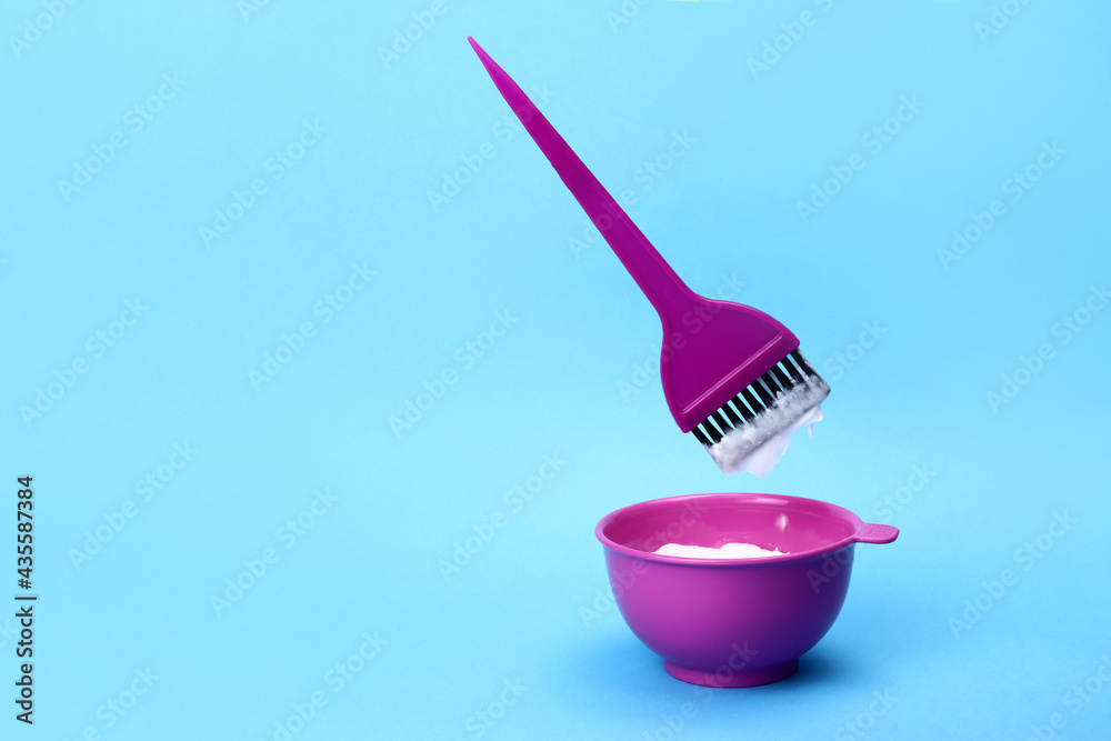 brush levitating over a plastic bowl of hair dye on a blue background brush levitating over a plastic bowl of hair dye on a blue background