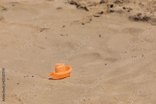 A small toy boat, belonging to a child, lies forgotten in the wet sand, near the shore, on the beach of Torrenostra, Mediterranean Sea, Castellon province, Spain.