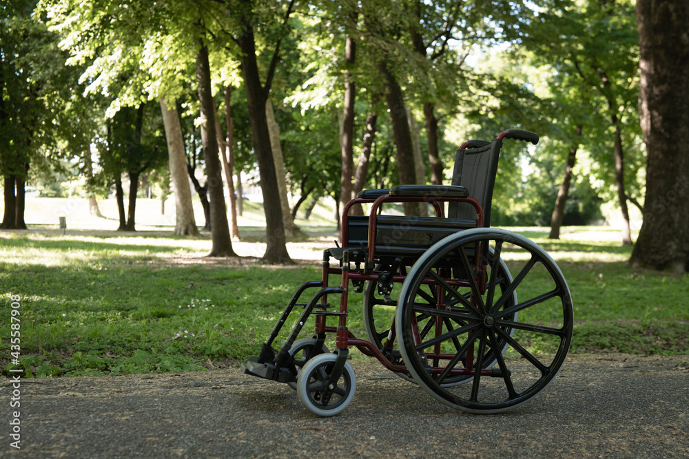 Cinematic shot of empty wheelchair surrounded by nature in green park in sunny day. Concept of life, miracle, healed person, disability, handicap, paraplegic
