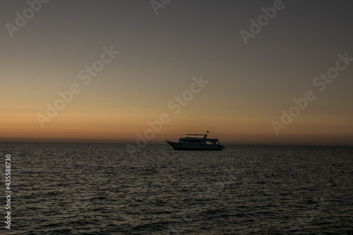 Red sunrise sky at sea and silhouettes of ships sailing on the sea. © Maria