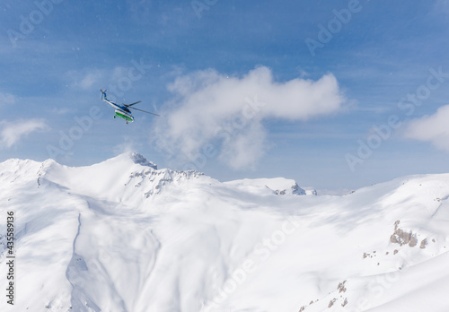 Helicopter flies into bare sky against snow mountains photo
