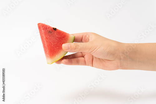 The girl's hand is holding sliced watermelon