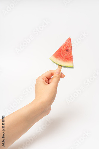 The girl's hand is holding sliced watermelon