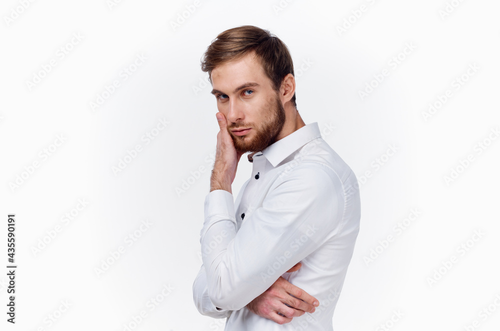 handsome young man in shirt touches his face with hand side view light background handsome young man in shirt touches his face with hand side view light background