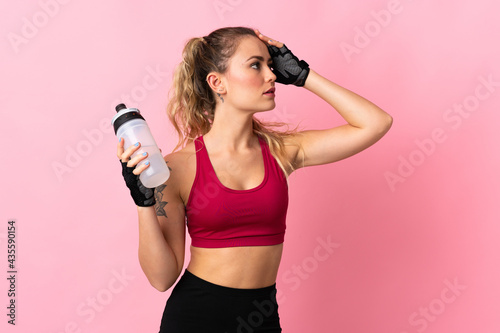 Fototapeta Naklejka Na Ścianę i Meble -  Young Brazilian woman isolated on pink background with sports water bottle