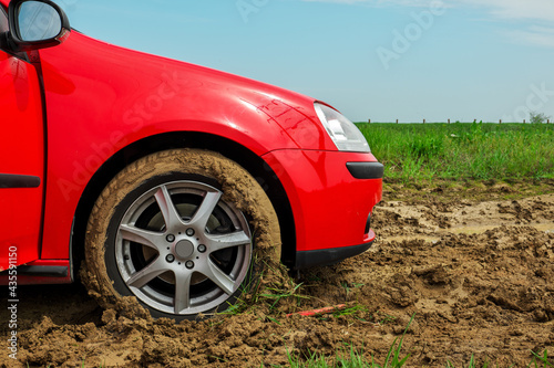 The red car stuck in the mud. Can not fall out of the mud