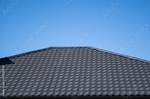 Brown corrugated metal profile roof installed on a modern house. The roof of corrugated sheet. Roofing of metal profile wavy shape. Modern roof made of metal. Metal roofing.