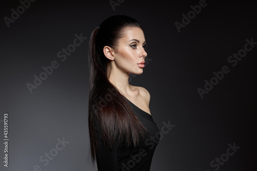 Classic makeup on woman face, beautiful big eyes. Fashion Perfect makeup, expressive eyes on girl face, smooth black eyebrows, licked brunette hair. Portrait woman on dark background