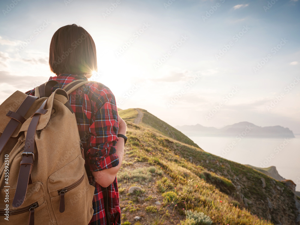 A young Asian woman with a backpack hiking in the summer.