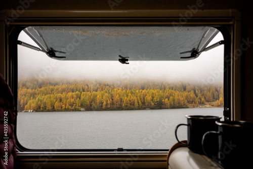 Camping Pause Kaffee Tee Tasse mit Blick aus dem Fenster auf See und herbstlichen Wald