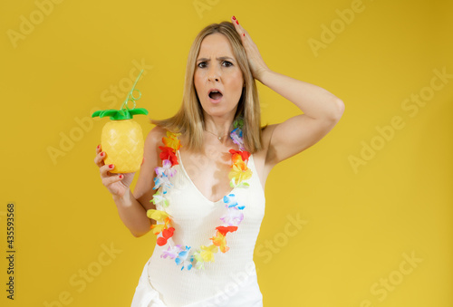Excited woman in swimsuit showing pineapple isolated over yellow background.
