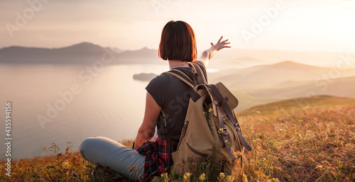 A young Asian woman with a backpack hiking in the summer.