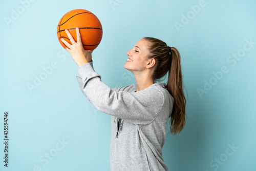 Young caucasian woman isolated on blue background playing basketball