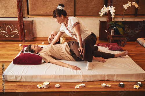 Woman twisting her body during Thai yoga massage
