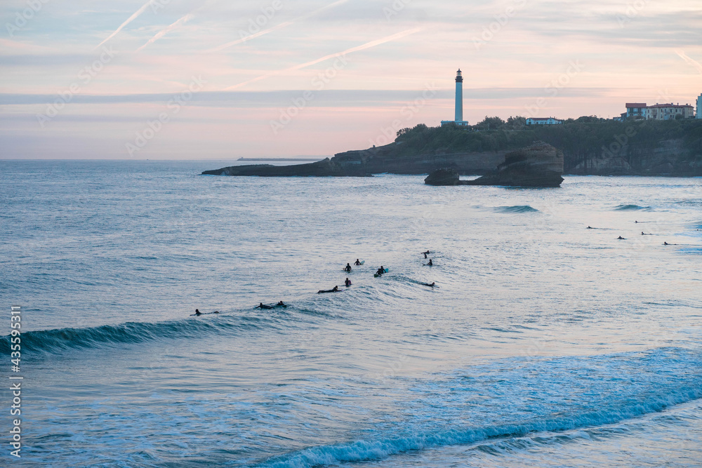 Surfeurs à la grande plage de Biarritz avec le phare sunrise