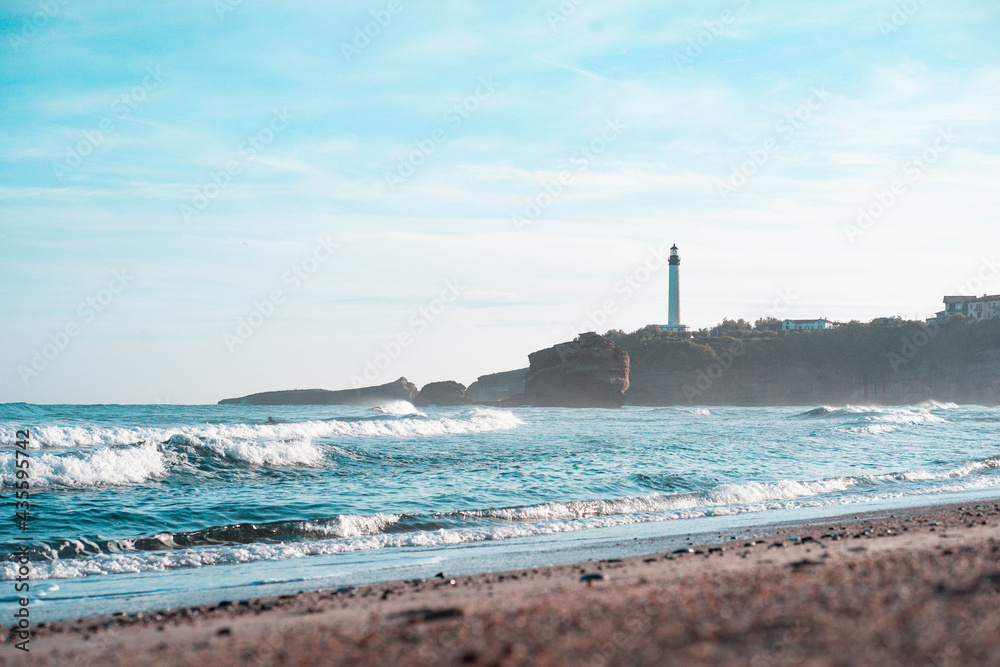Surfeur sur la grande plage de Biarritz avec le phare et des vagues