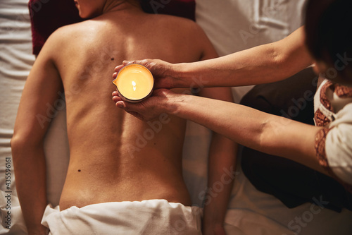 Fotografie Massage candle above naked back of beauty parlour visitor