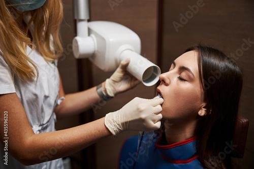 Relaxed female is undergoing dental x-ray examination