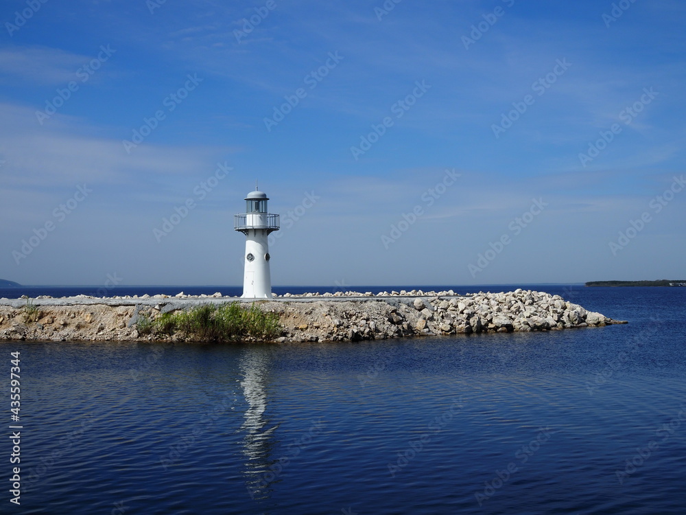 white washed lighthouse looks over the deep blue ocean