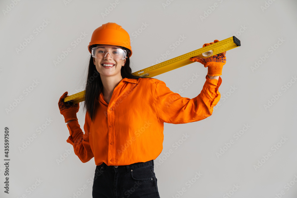 Young woman in safety glasses and helmet posing with building tool
