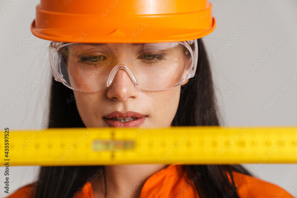 Young woman in safety glasses and helmet posing with tape measure Young woman in safety glasses and helmet posing with tape measure