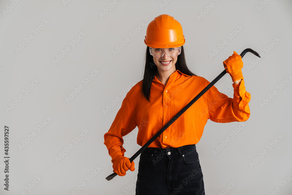 Young woman in safety glasses and helmet posing with building tool Young woman in safety glasses and helmet posing with building tool