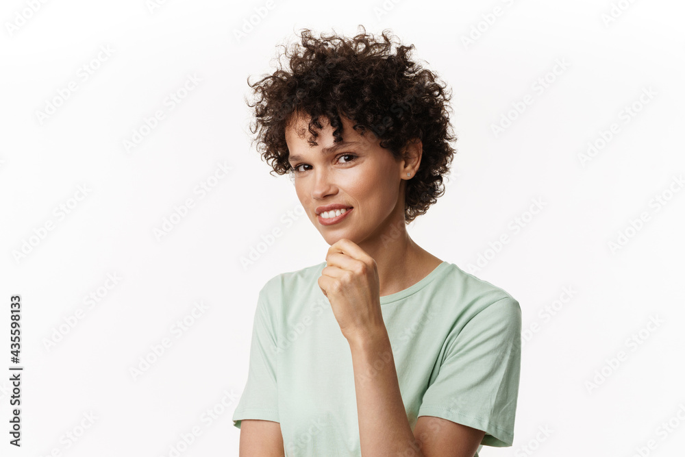 Young curly brunette woman smiling and looking at camera