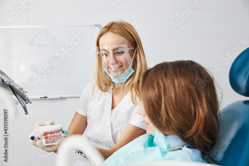 Pleasant dental doctor explaining correct way of brushing teeth