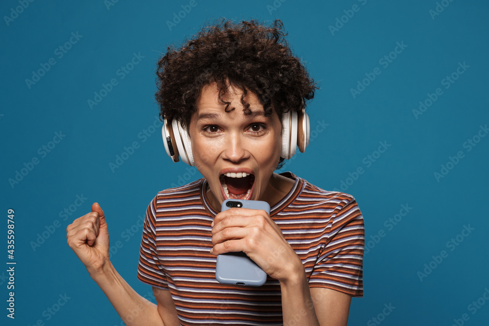 Young woman screaming while using cellphone and headphones Young woman screaming while using cellphone and headphones