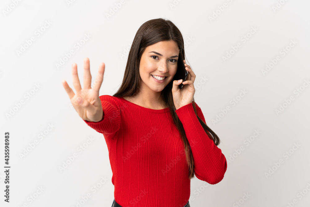 Teenager Brazilian girl using mobile phone over isolated white background happy and counting four with fingers Teenager Brazilian girl using mobile phone over isolated white background happy and counting four with fingers