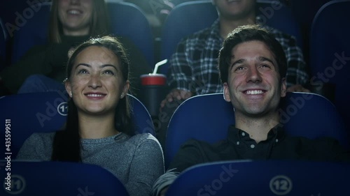 Movie theatre audience - Young couple enjoying the movie, smiling and laughing.