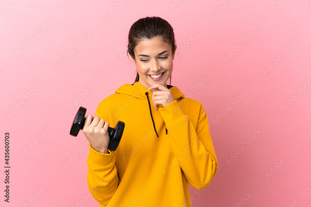 Young sport girl making weightlifting over isolated pink background looking to the side and smiling Young sport girl making weightlifting over isolated pink background looking to the side and smiling