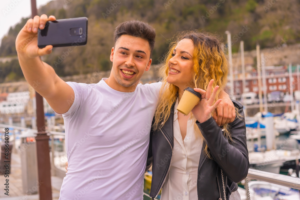 Lifestyle of a couple sightseeing and enjoying the holidays. Strolling through a seaport and taking a photo Lifestyle of a couple sightseeing and enjoying the holidays. Strolling through a seaport and taking a photo