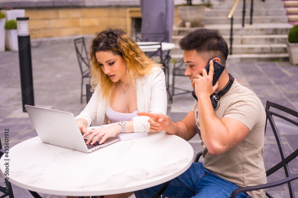 Young entrepreneurs doing teamwork. Working on the internet with the computer on a terrace of a bar Young entrepreneurs doing teamwork. Working on the internet with the computer on a terrace of a bar